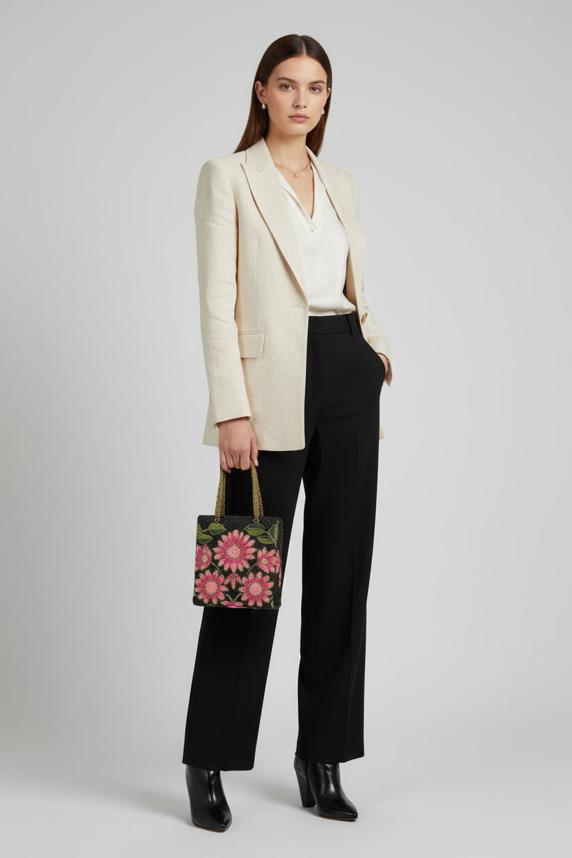 A pink floral handcrafted tote bag with glass bead embroidery on a dark base, displayed on a wooden surface