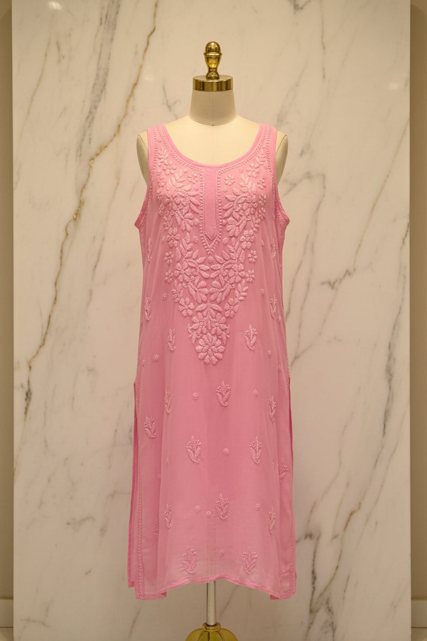 A pink sleeveless tunic dress with intricate floral embroidery and lace detailing, hanging on a white hanger in a retail setting.