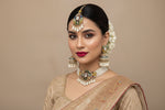 A portrait of a girl wearing an ornate multi-color stone choker set. The warm brass metal contrasts beautifully with the white Kundan and delicate pearls, creating a sophisticated ethnic look.