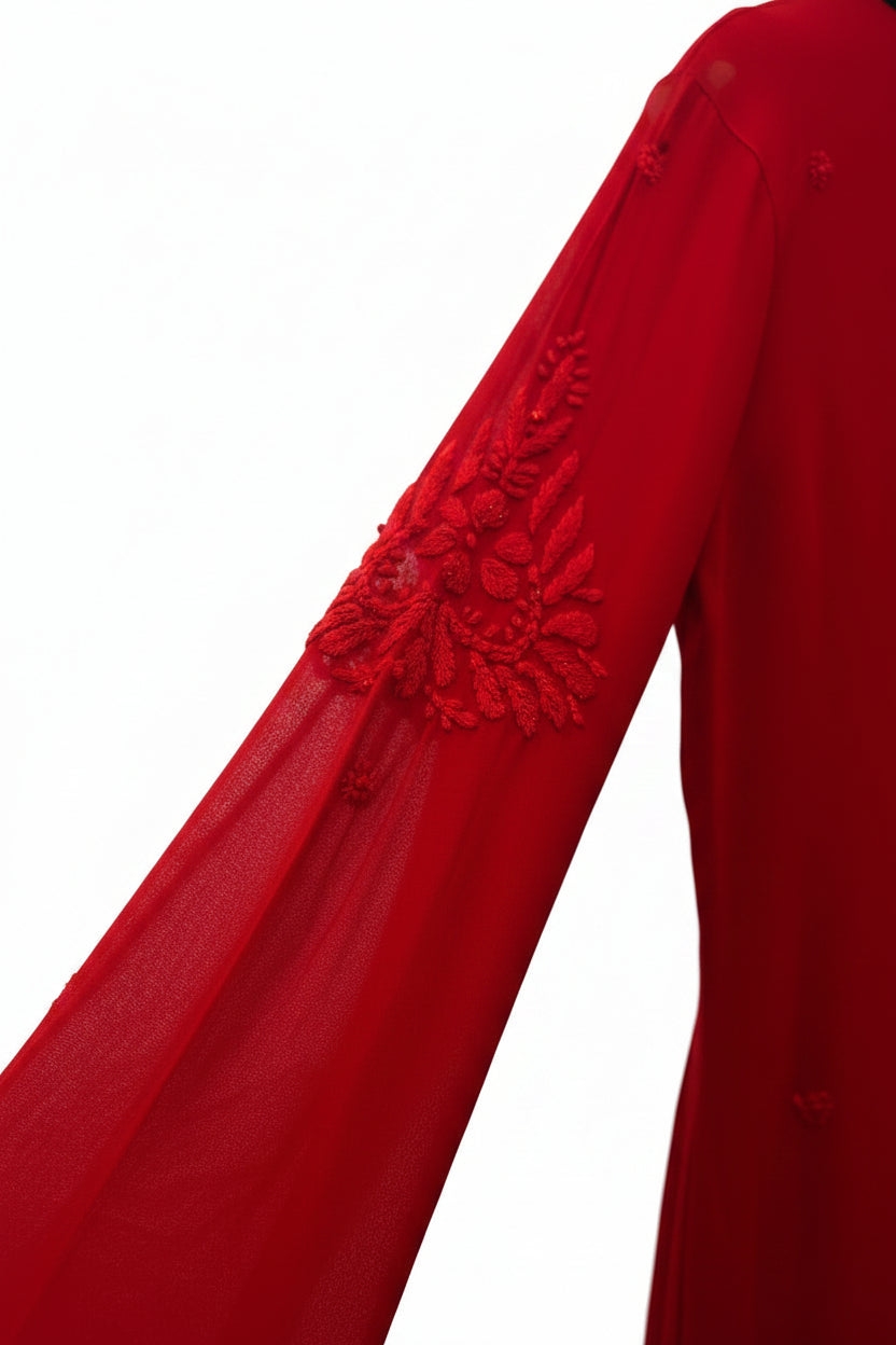 A red long-sleeve dress with intricate floral embroidery on the sleeves, hanging on a white hanger against a black garment on a clothing rack.