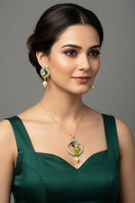 A rhodium-gold plated brass pendant with a peacock design accompanied by earrings, featuring vibrant green, blue, and gold enamel accents, as well as white and turquoise AD stones sparkling embellishments. Party wear jewellery set.
