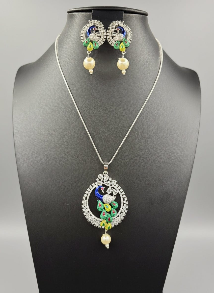 A rhodium-silver plated brass pendant with a peacock design accompanied by earrings, featuring vibrant green, blue, and gold enamel accents, as well as sparkling white AD stones embellishments.