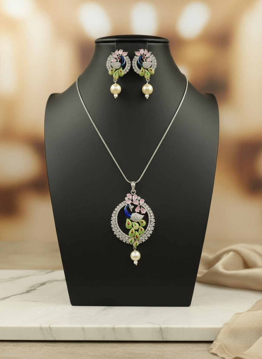 A rhodium-silver plated brass pendant with a peacock design accompanied by earrings, featuring vibrant green, blue, and gold enamel accents, as well as sparkling white and pink ad crystal embellishments. Party wear jewellery set. 