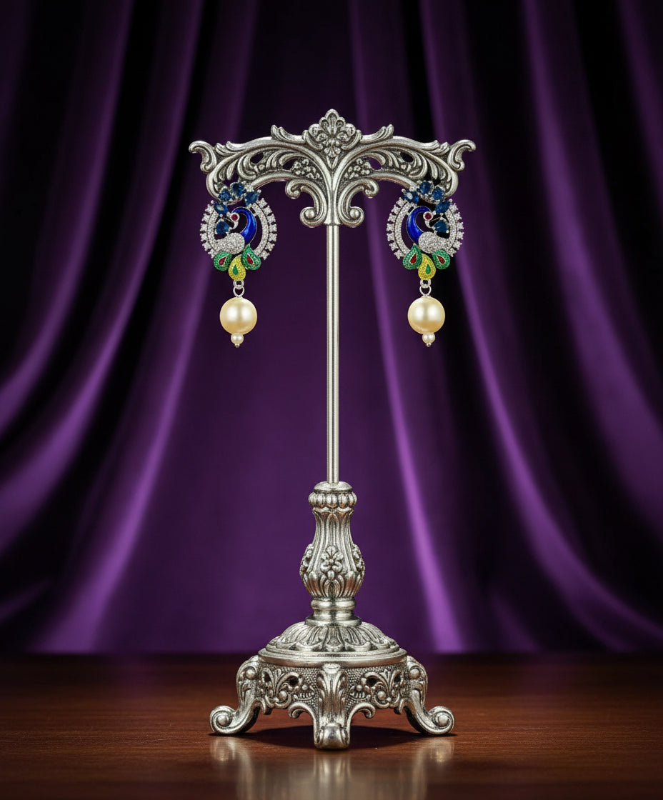 A rhodium-silver plated peacock design accompanied earrings, featuring vibrant green, blue and yellow enamel accents, as well as sparkling white and blue AD crystal stones. Earrings design is focused. 