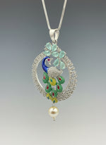 A rhodium-silver plated peacock design pendant with silver chain ,featuring vibrant green, blue, enamel accents, as well as sparkling crystal white and turquoise stones. Pendant with silver chain design is focused. 