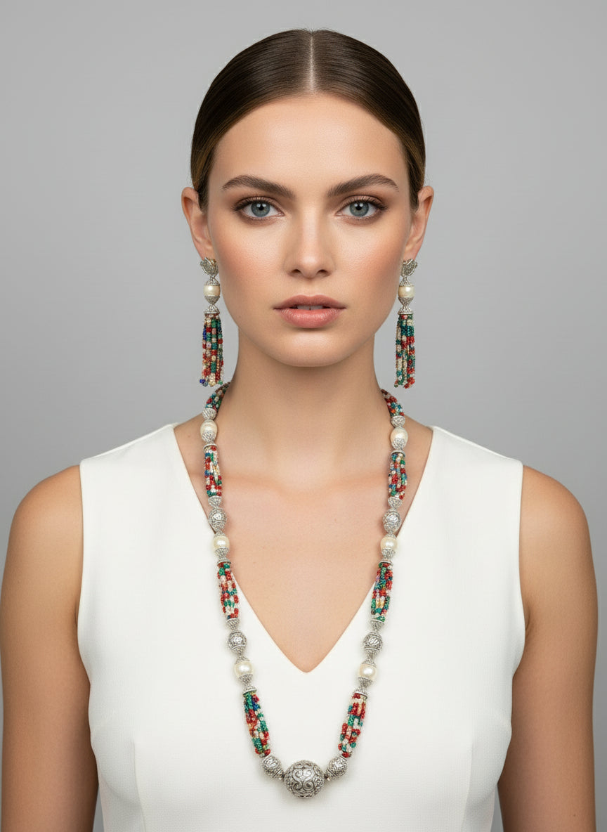 A set of jewellery featuring a long necklace with multi-coloured glass beads and metallic accents, paired with matching earrings, displayed on a mannequin bust.