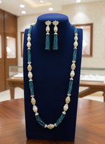 A set of jewellery featuring a long necklace with navy blue glass beads and metallic accents, paired with matching earrings, displayed on a mannequin bust. Party wear set. 