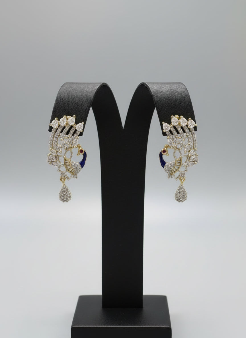 A set of peacock-shaped earrings. The earrings are detailed with blue enamel and has sparkling white and AD stones crystal embellishments. Party wear Earrings. Earrings are in focused.