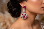 A side profile view of a model wearing vibrant fuchsia and crystal chandelier earrings, as shown in the product image.