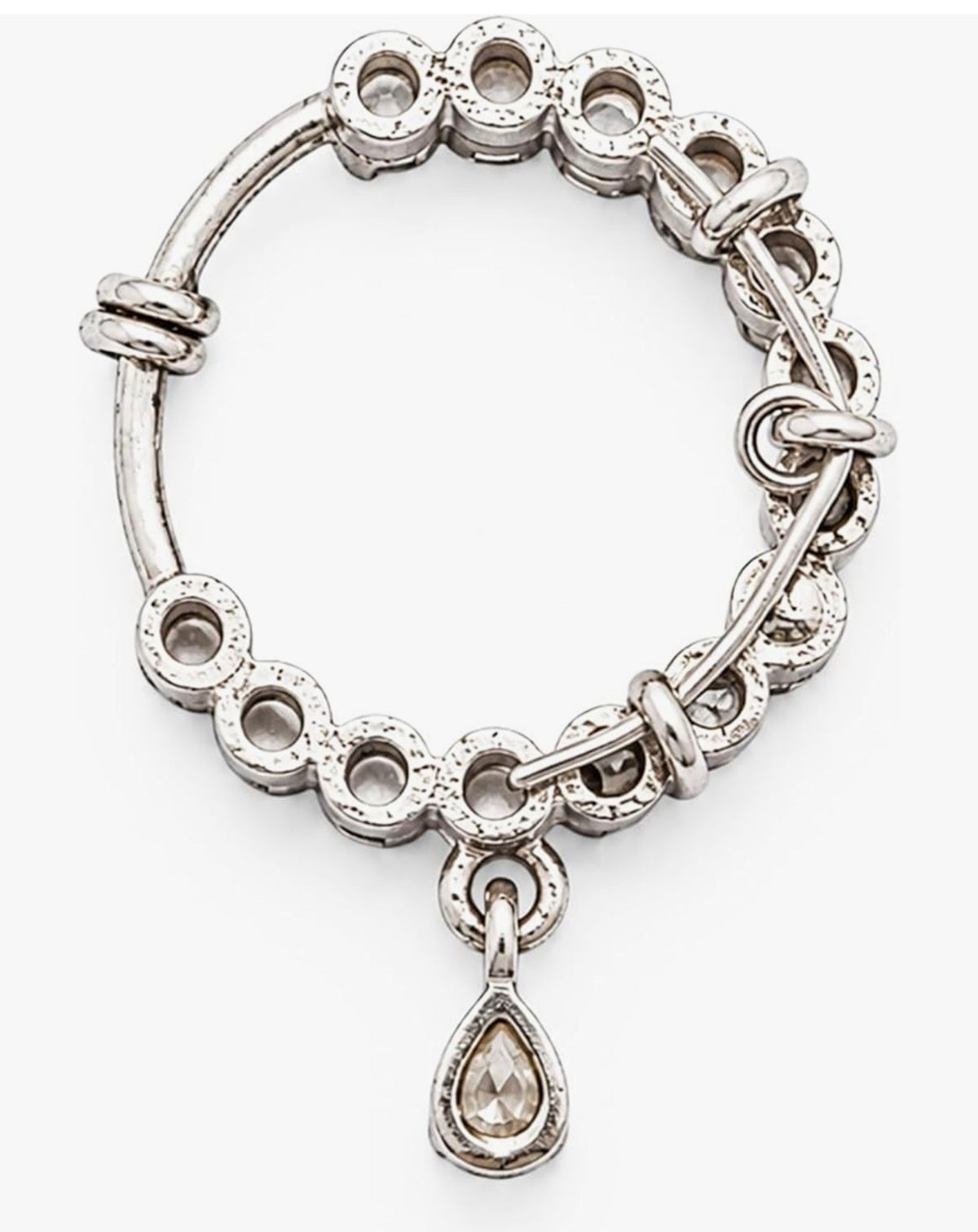 A silver-toned bangle bracelet featuring a series of textured circular links, some adorned with small clear stones, and a dangling teardrop-shaped clear gemstone charm, shown on a plain white background.