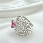 A silver-toned statement ring featuring a large, ornate pavé-set design with a prominent rectangular pink gemstone on the side, resting on a dark textured surface.