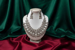 A silver-toned traditional statement necklace with matching drop earrings with fish hook displayed on a black velvet jewellery bust. The necklace features multiple stylized bird motifs with intricate filigree detailing and dangling bead chains.