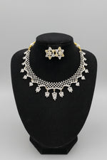 A silver and gold jewellery set displayed on a black velvet mannequin bust, featuring a lace-like collar necklace with leaf-shaped charms and a matching Star shape studs. 