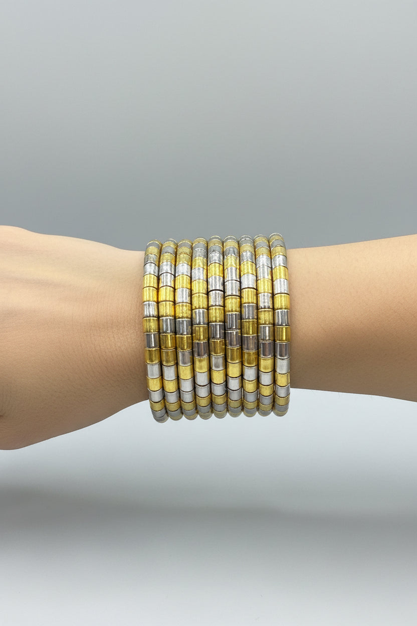 A stack of wide bangle bracelets with alternating translucent yellow and silver metallic segments, held in a hand against a black background.
