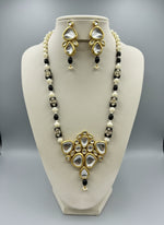 A traditional bridal necklace set displayed on a mannequin, featuring black and gold colors with intricate detailing and pearl beads.