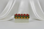 A white clutch bag with multi-coloured nano glass beads patterns, hand embroidered, displayed outdoors.