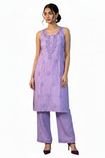 A woman modeling a lavender purple embroidered kurta and matching wide-leg trousers against a white patterned backdrop.