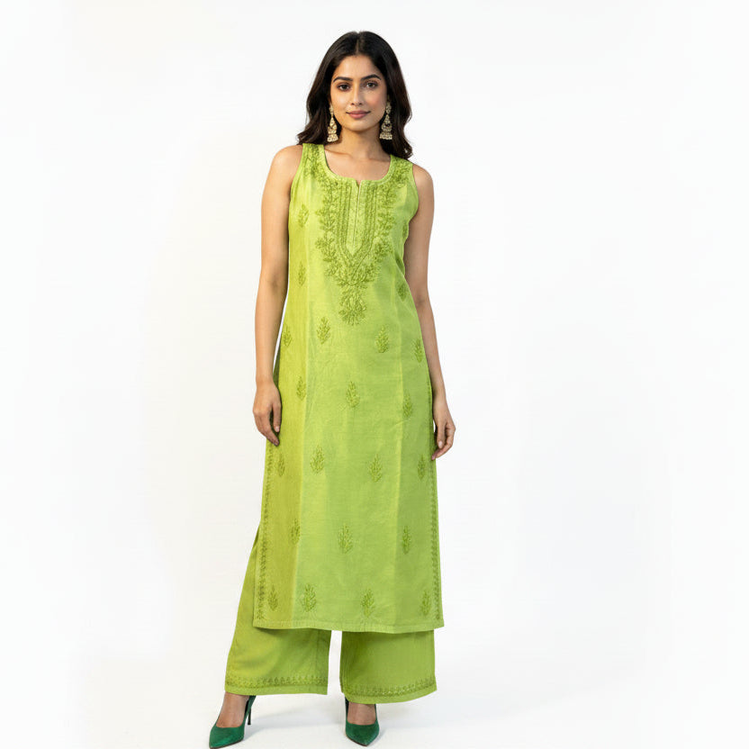A woman modelling a lime green sleeveless kurta with matching green pants, standing against a white patterned backdrop.