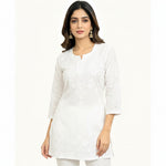 A woman modelling a bright pink embroidered kurta with three-quarter sleeves and white pants, posed against a plain white background.