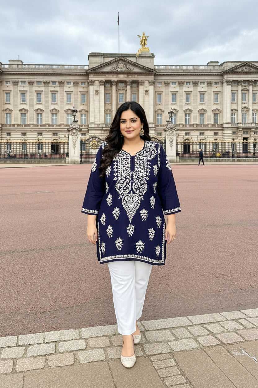 A woman modelling a navy blue kurta with intricate white embroidery, standing in front of Buckingham Palace.