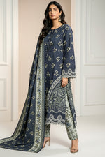 A woman models a three-piece navy blue traditional outfit with beige floral prints and intricate lace trim, consisting of a long kurta, matching trousers, and a draped dupatta, set against a neutral studio background.