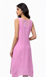 A woman shown from the back wearing a sleeveless pink kurta with subtle embroidery and a sheer neckline, paired with white pants, against a plain white background.