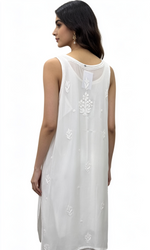 A woman shown from the back wearing a sleeveless white tunic with delicate embroidered details, set against a plain white background.