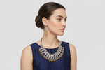 A woman wearing a silver-toned statement necklace with gold-toned beaded accents and matching dangling earrings, shown against a light grey background with measurement callouts and text indicating product dimensions and weight.