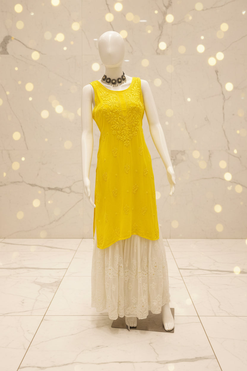A yellow sleeveless dress displayed on a white mannequin inside a store window, with a white lace skirt or overlay attached. The mannequin is positioned in front of a glass display case on a yellow floor.