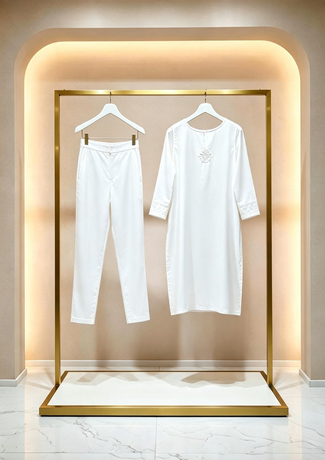 Hanging display of the white handcrafted sleeveless Chanderi silk Chikankari co-ord set, featuring the tunic and matching trousers hanging side-by-side on white hangers within an illuminated gold boutique rack.