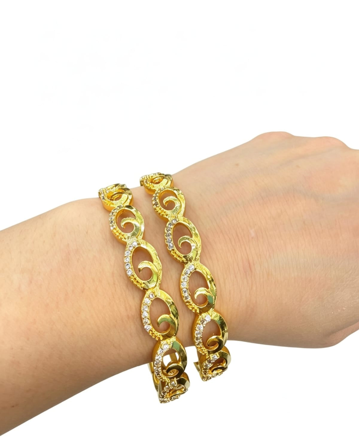 On-wrist display of two gold-toned bangles featuring an interlocking oval swirl design studded with sparkling white American Diamonds.