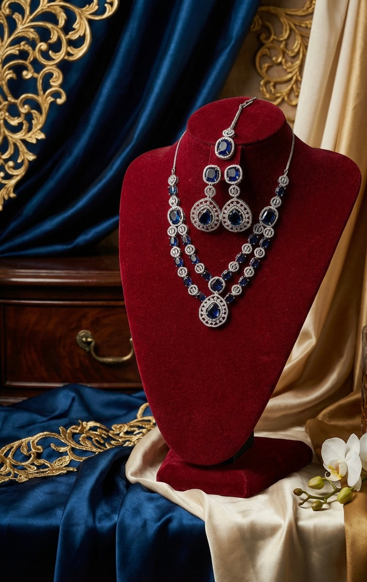 American Diamond necklace , earrings and maag tikka displayed on a red velvet stand with ornate background.