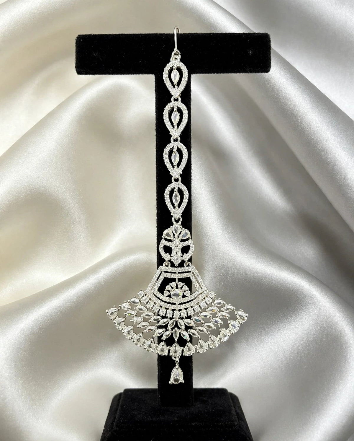 Anfal silver fan-shaped AD maang tikka with clear cubic zirconia stones, displayed on black stand — Famaza Couture premium silver bridal forehead jewelry.