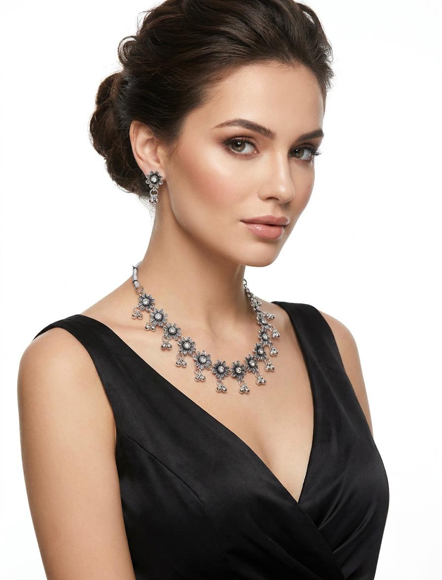 Model wearing an antique oxidized silver sunflower-motif necklace set featuring clear crystal centers and traditional triple-bead ghungroo drops on a silver dory cord.