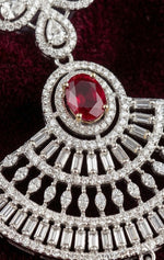 Close-up view of the Aria luxury earring featuring a vibrant oval red stone centerpiece surrounded by precisely set rectangular baguette and round cz diamonds.