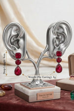 Magenta statement drop earrings featuring tiered teardrop and round gems, set in polished rose gold, luxury jewelry display.