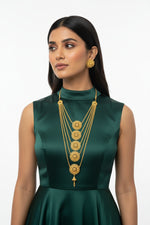 A model wearing the Ayesha Eternal gold-plated multi-layered necklace set with matching stud earrings by Famaza Couture, featuring intricate circular motifs against a white background.