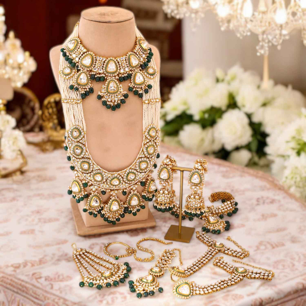 Ornate gold and green jewelry set on a mannequin and table with flowers in the background