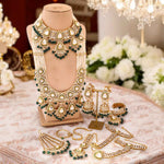 Ornate gold and green jewelry set on a mannequin and table with flowers in the background