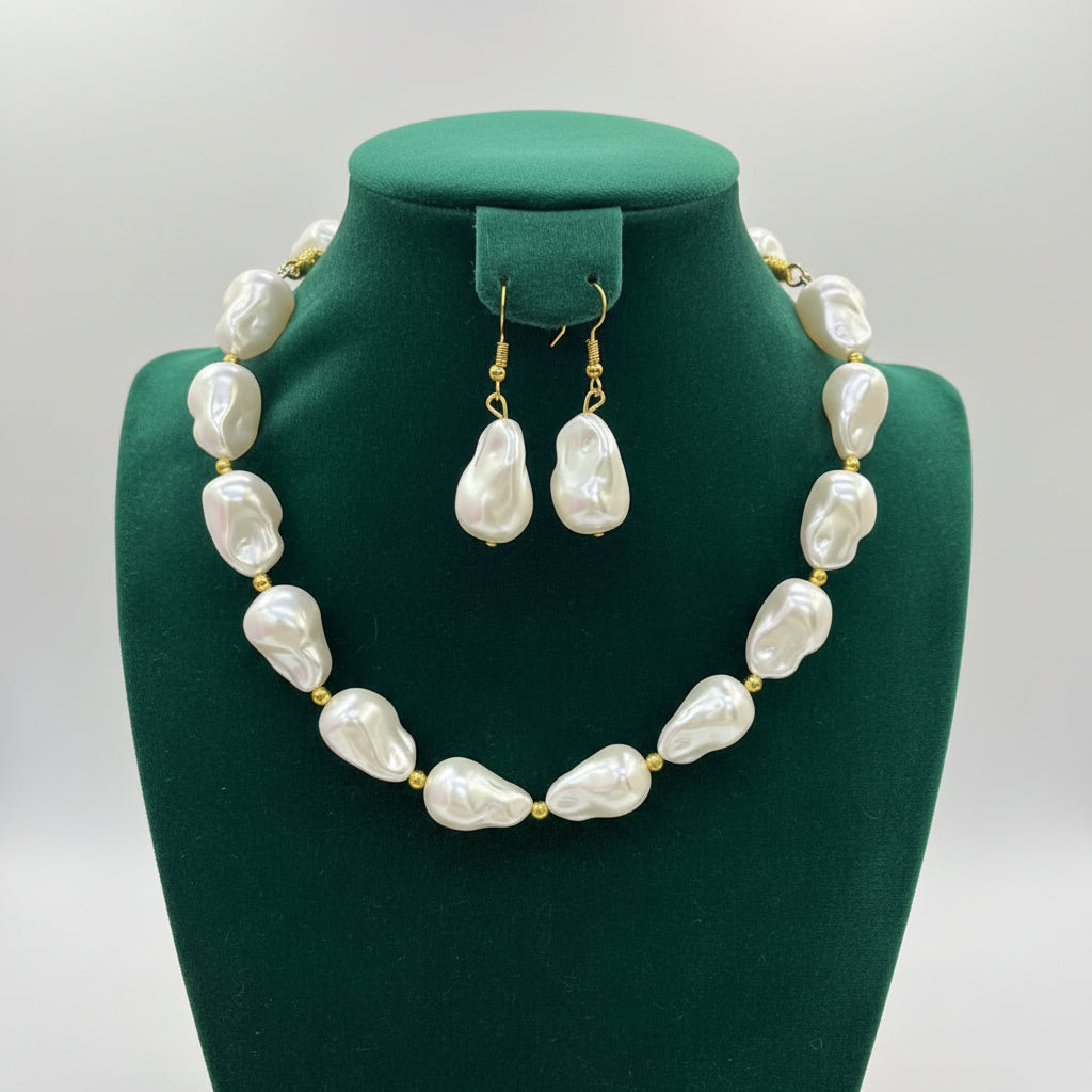 A jewelry set featuring a statement necklace of large, irregular white baroque pearls with gold-tone spacer beads and matching drop earrings, displayed on a black mannequin bust.