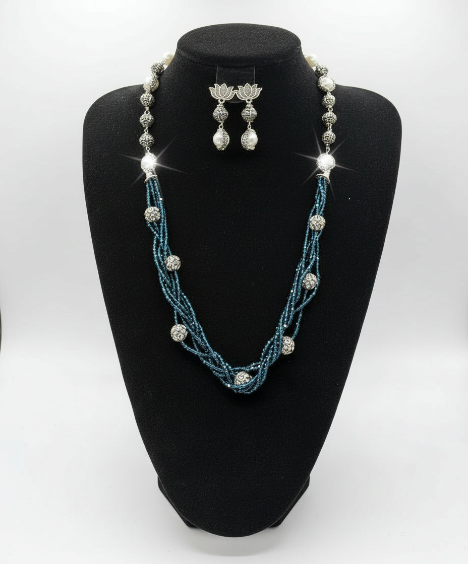 Beaded mala with silver and pearl beads in on both sides start and drop is designed with navy blue nano glass bead with silver ball beads, along withLotus design earrings with silver and pearl beads in drop. Oxidised party wear jewellery set. 