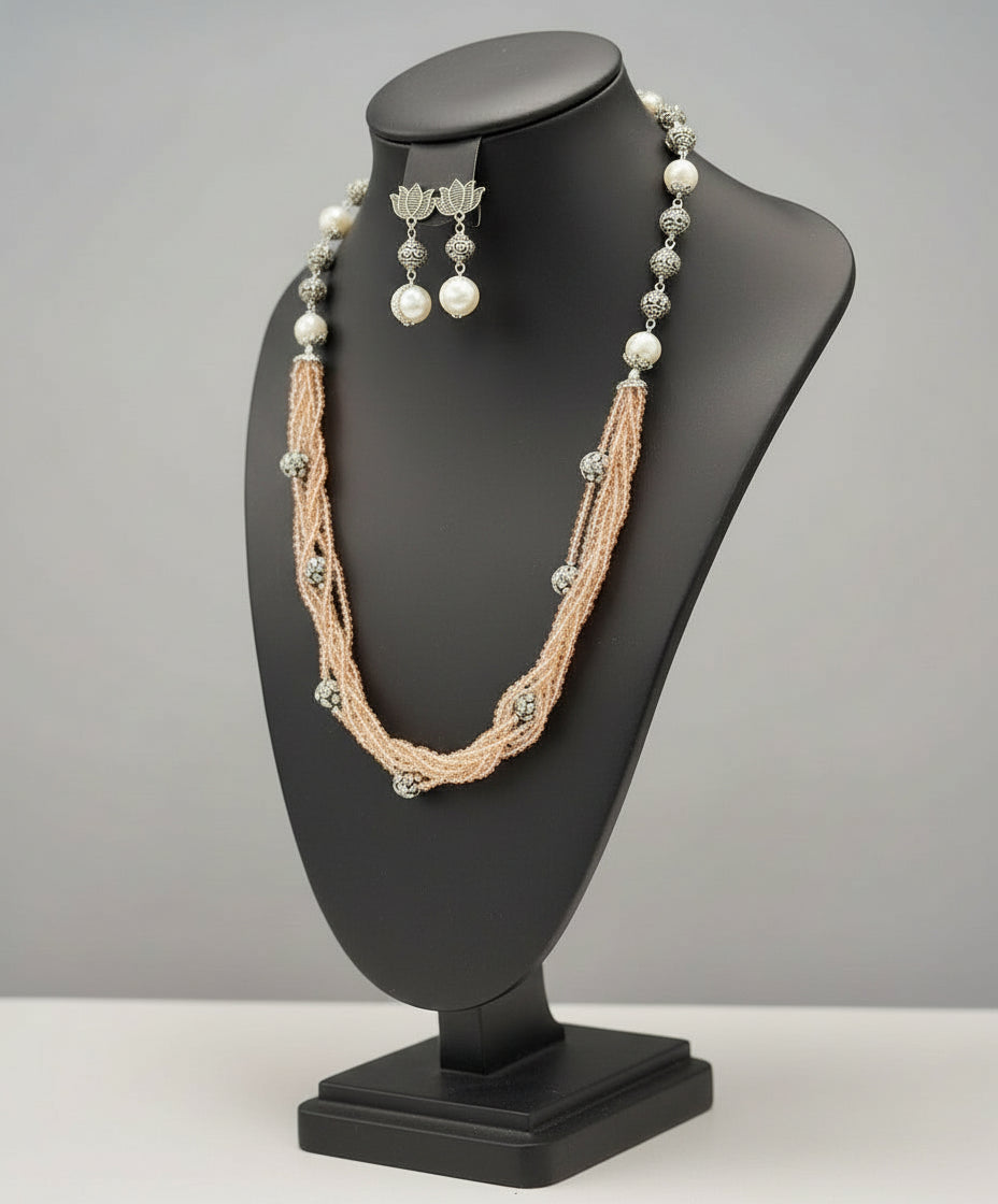 Beaded mala with silver and pearl beads in on both sides start and drop is designed with peach colour nano glass bead with silver ball beads, along withLotus design earrings with silver and pearl beads in drop. Oxidised jewellery set. 