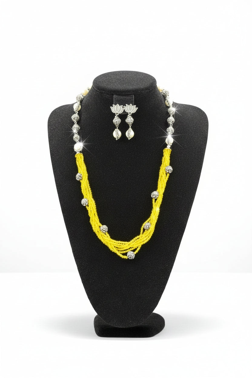 Beaded mala with silver and pearl beads in on both sides start and drop is designed with yellow nano glass bead with silver ball beads, along withLotus design earrings with silver and pearl beads in drop. Oxidised jewellery set. 