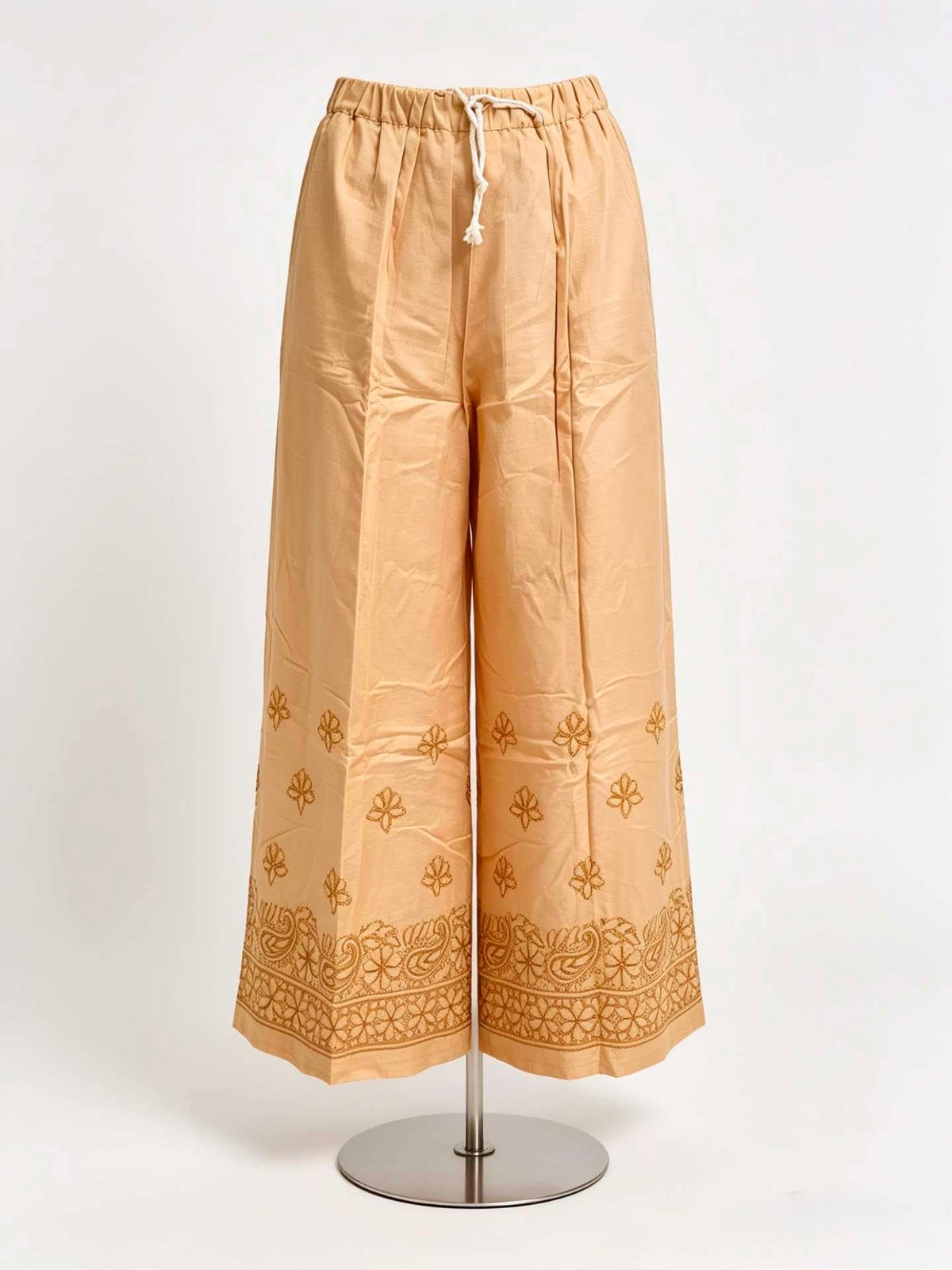 Beige pants with gold embroidery on a white background