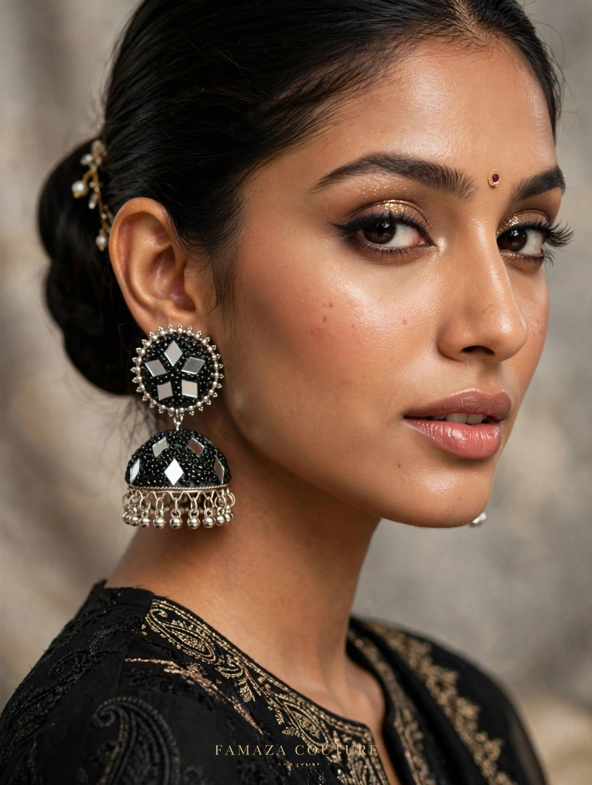 Close-up of South Asian woman wearing black mirror work jhumka earrings with silver-toned frame, beaded border, and hanging ghungroo — Famaza Couture.