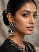 Close-up of South Asian woman wearing black mirror work jhumka earrings with silver-toned frame, beaded border, and hanging ghungroo — Famaza Couture.