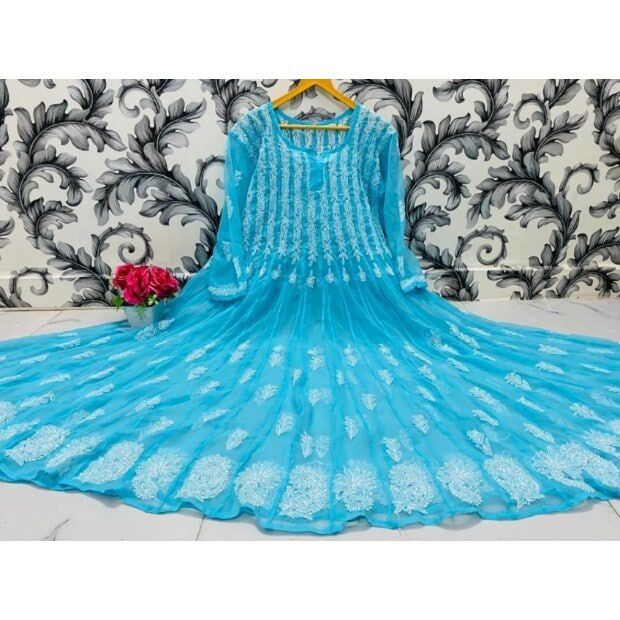 Blue embroidered dress on a hanger against a decorative wall.