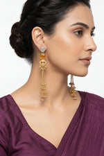  Bold statement earrings with a gold-textured wreath design and a vibrant orange stone pendant on a model.