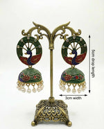 Bottle green Meenakari peacock earrings on a display stand showcasing the intricate hand-painted bird motif.
