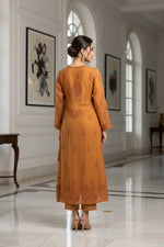 Brown dress with floral patterns on a gray surface with small decorative items.